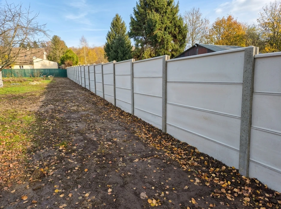 Clôture en béton préfabriqué neuve, posée en limite de propriété sur terrain extérieur en automne