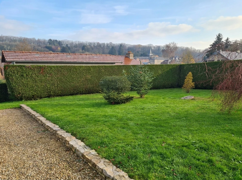 Massif paysager extérieur bordé d'une bordure courbe en briques jaunes, rempli de paillage en écorces de pin maritime brun-rouge